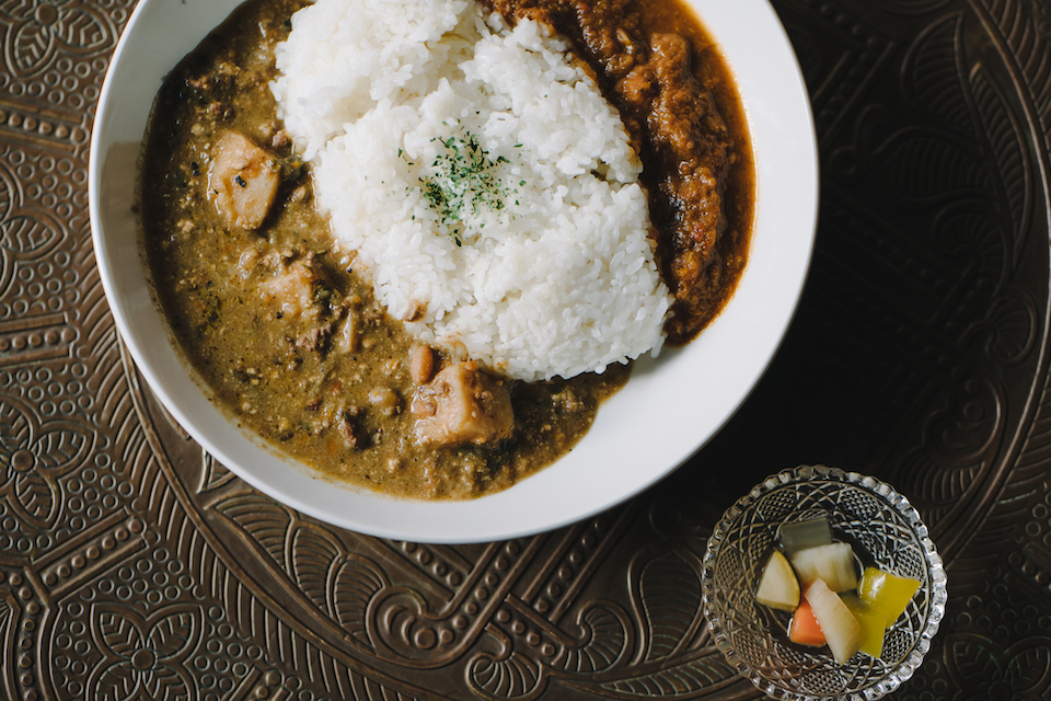 しろくてまるいふかざらのまんなかにごはんがもりつけてあり、りょうわきに２しゅるいのカレーがかかっている。