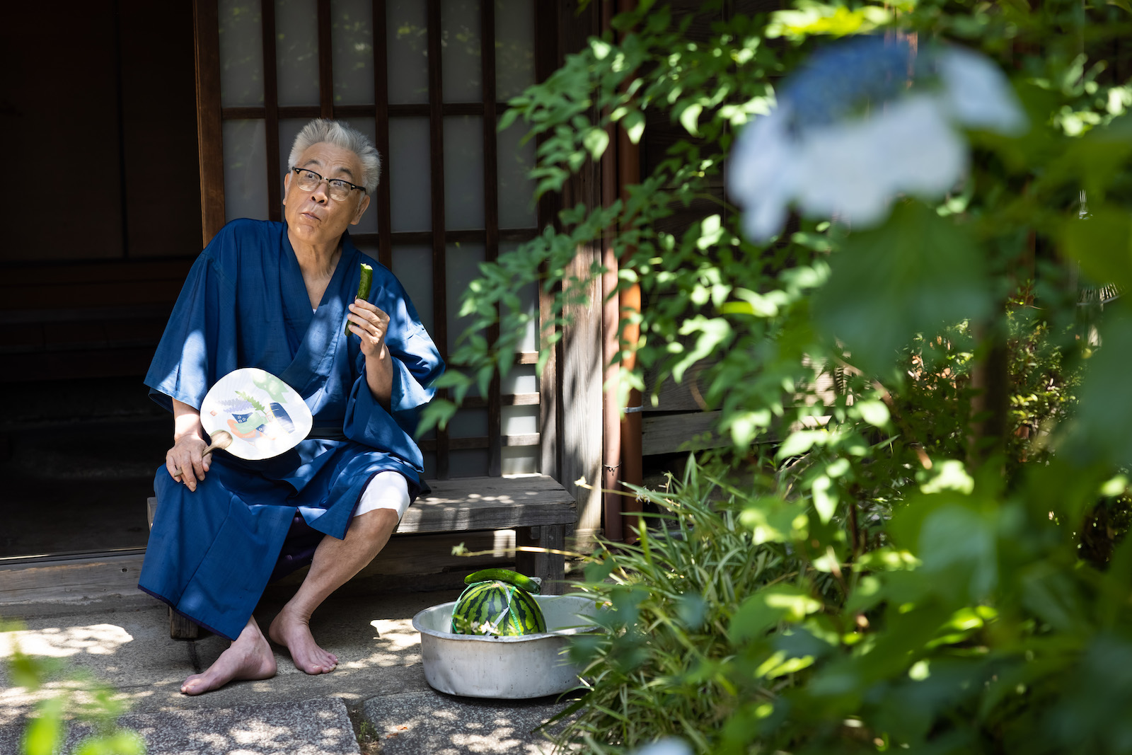 日本家屋の玄関前で、きゅうりをかじる浴衣姿のイッセー尾形さん