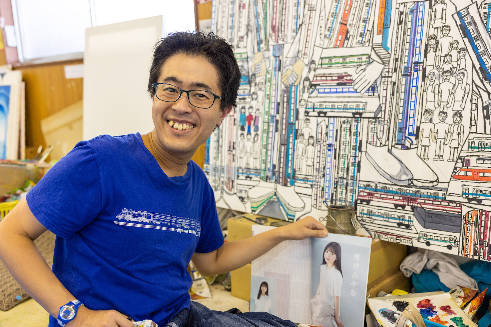 制作中の作品の前で、雑誌を手にカメラに笑顔を見せてくれた早川さん