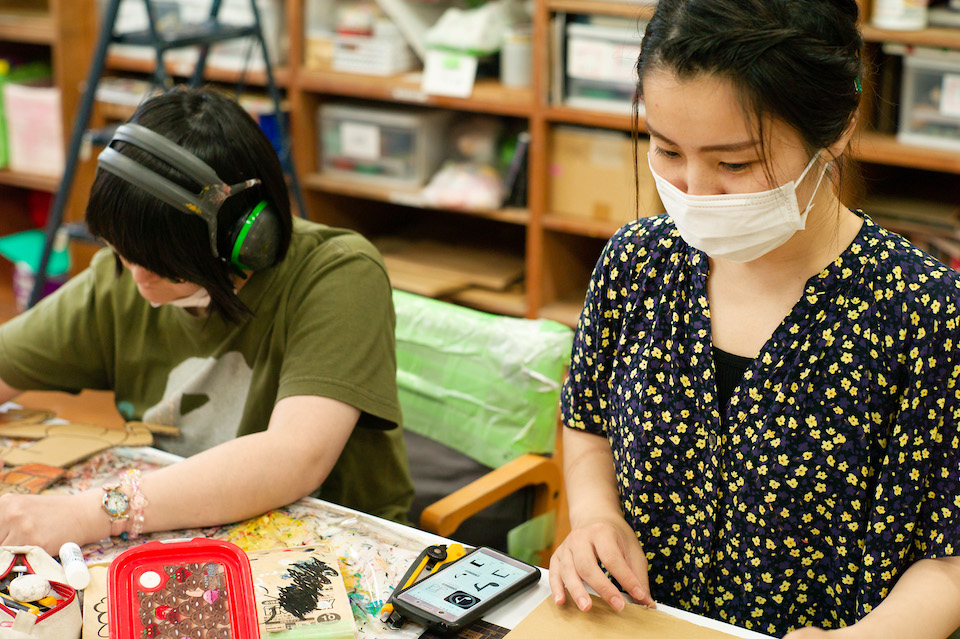 黙々と同じ机で作業をする宿利真希さんと女性スタッフ