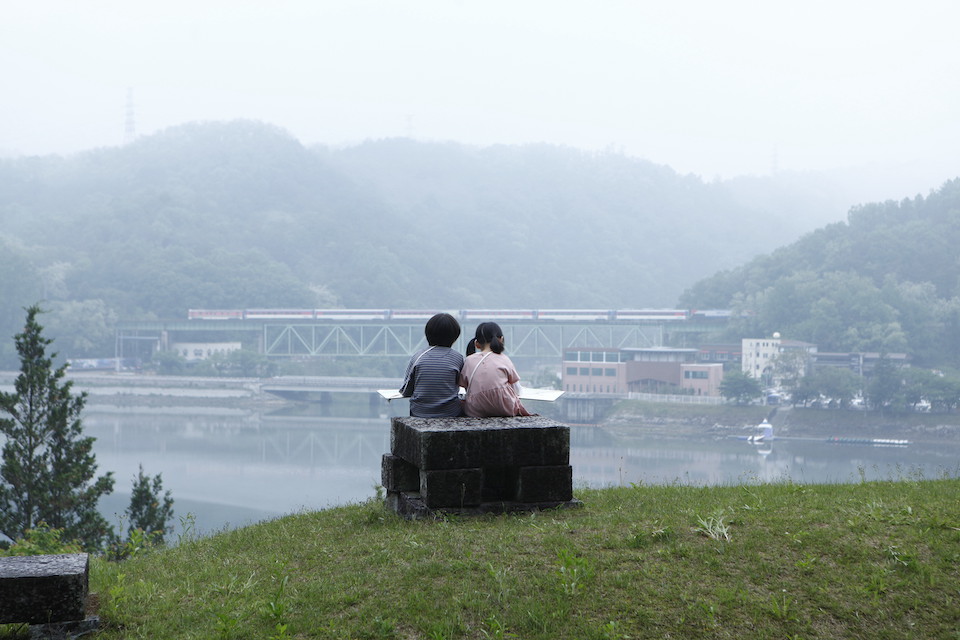 湖の前で座る幼い姉弟。