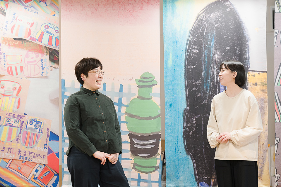 【写真】アート作品が描かれた壁の前で話をする柴崎由美子さんと髙橋梨佳さん