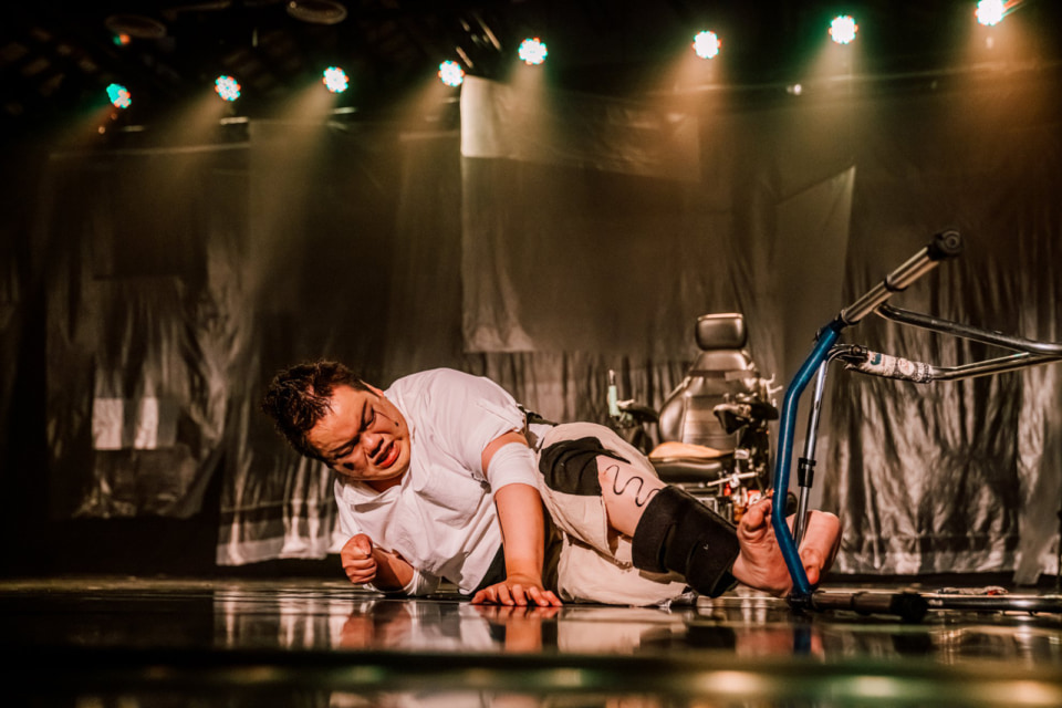 [Photograph]On stage, a person who has difficulty walking is on the floor performing a scene.