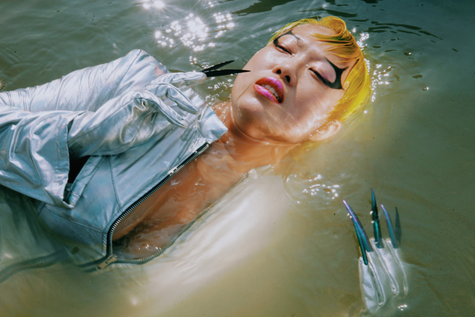 [Photograph]Betty Apple floats on water in a costume that looks like a mermaid from the future.