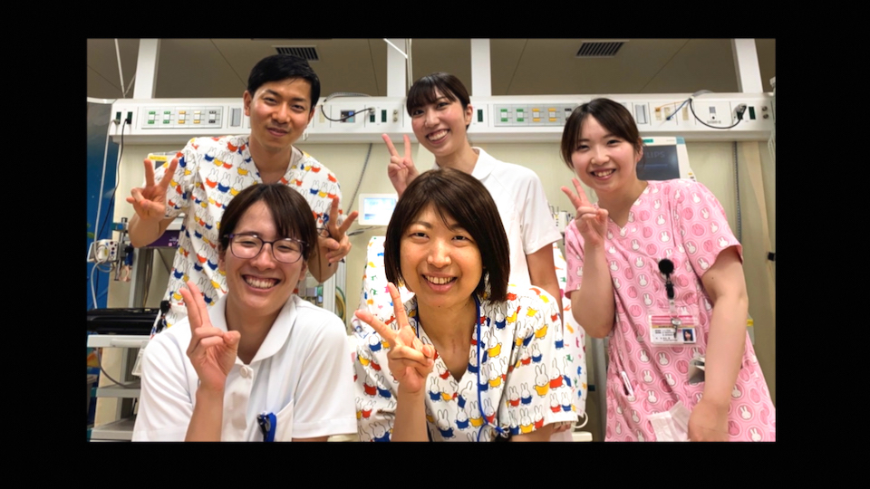 【写真】鈴木ゆずなさんと同僚の看護師たち。ゆずなさんを真ん中に、4名の同僚たちがにこやかにピースサインをして笑う。