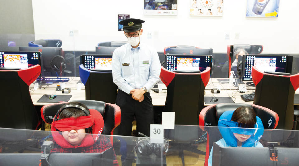 【写真】会場のジェクサー・eスポーツ ステーションJR松戸駅店内の様子。ゲーミングチェアがずらりと並ぶなかで、赤いアイマスクをつけたプレイヤーと、青いアイマスクを付けたプレイヤーがゲームをプレイしている。