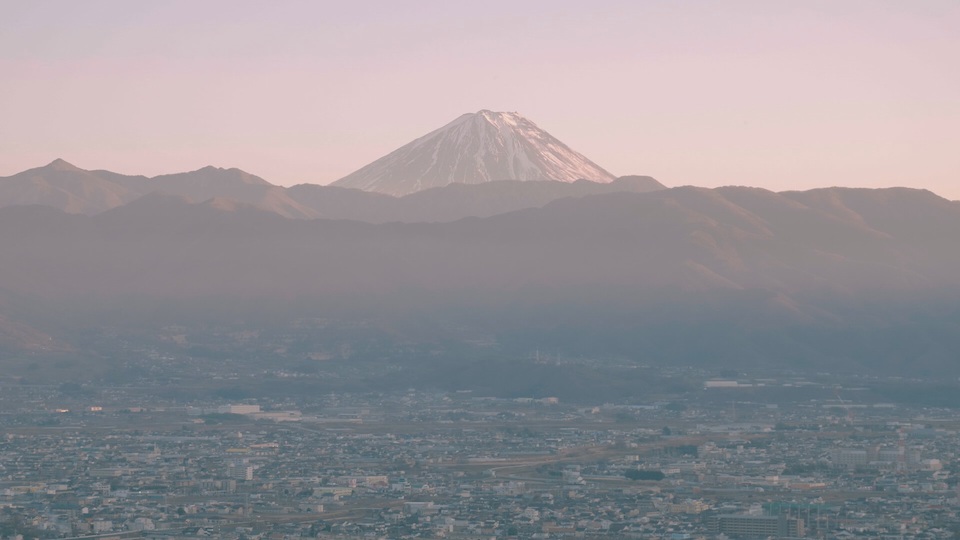 【写真】甲府の市街地を前景に、後方に大きくそびえる富士山を正面からとらえた様子。