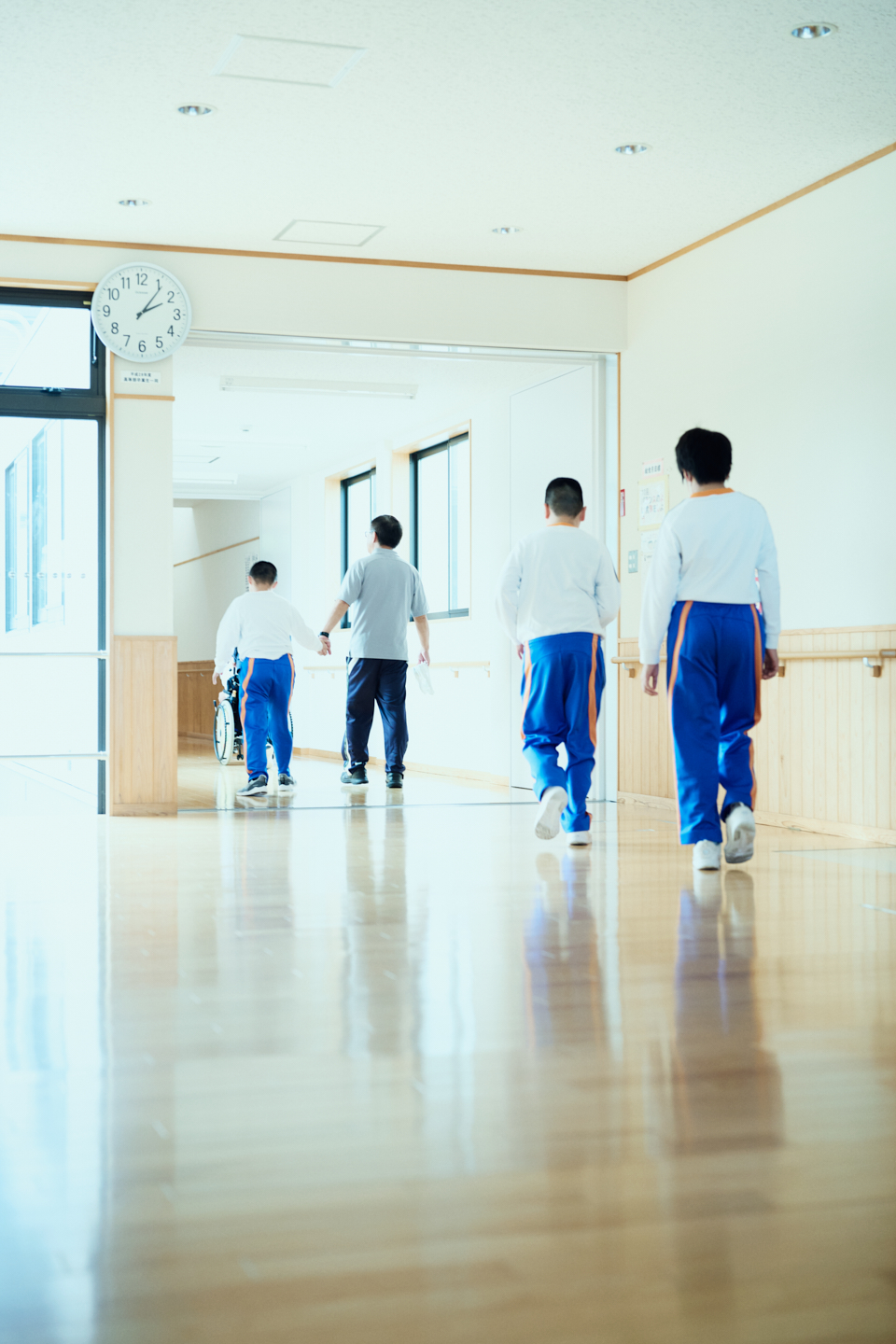 【写真】長濱哲哉さんが通う村山特別支援学校本校の廊下を、3人の生徒と1人の先生が一緒に歩いていく後ろ姿