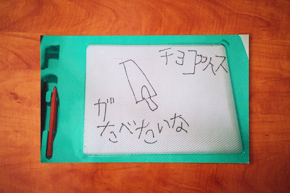 【写真】哲哉さんが小学生時代に用いていたお絵かきボード。「チョコアイスがたべたいな」の文字とアイスの絵が描かれている。