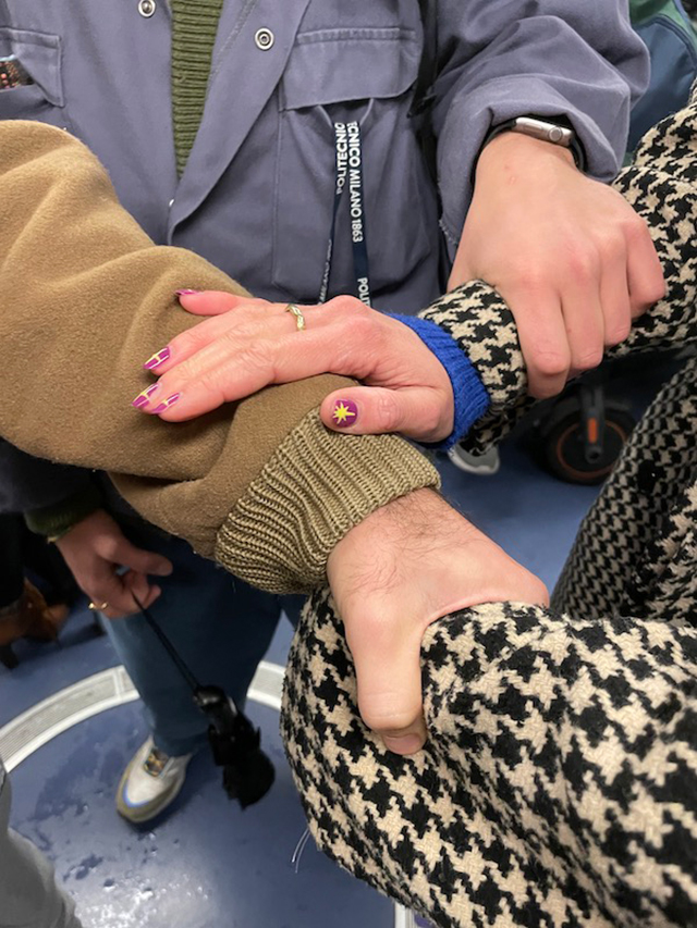 【写真】地下鉄のなかで、3人の人が互いの手首をつかんだり、手を添えたりしながら、支え合っているその手元の様子