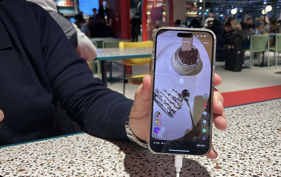 【写真】男性が充電器につながれたスマートフォンを見せている様子。画面にはTiktokにアップされたデザートの映像が映っている。